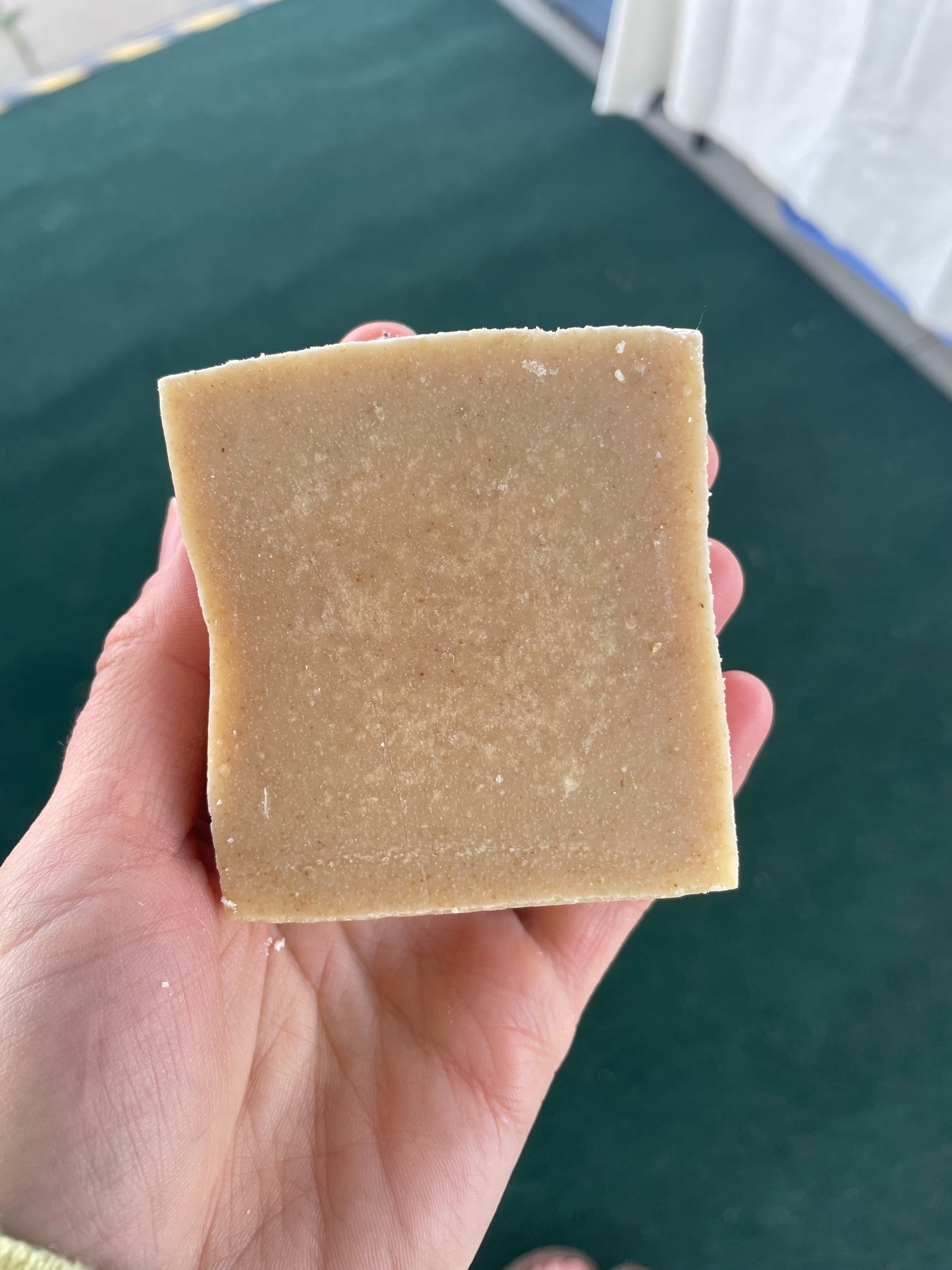 Hand holding a square bar of soap against a dark background