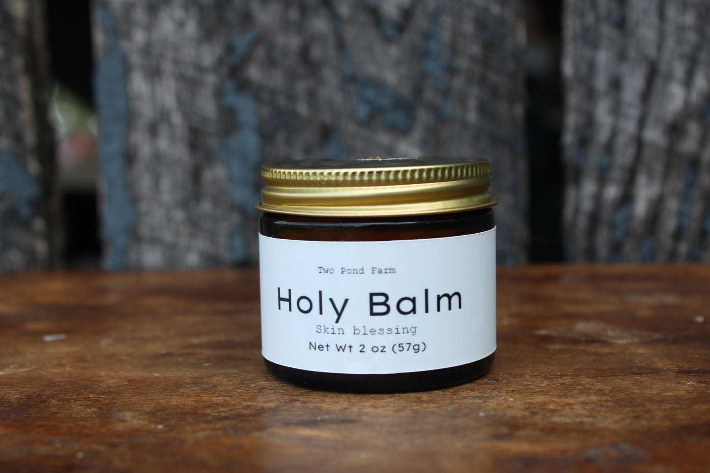 Jar of 'Holy Balm' on a wooden surface with a blurred background