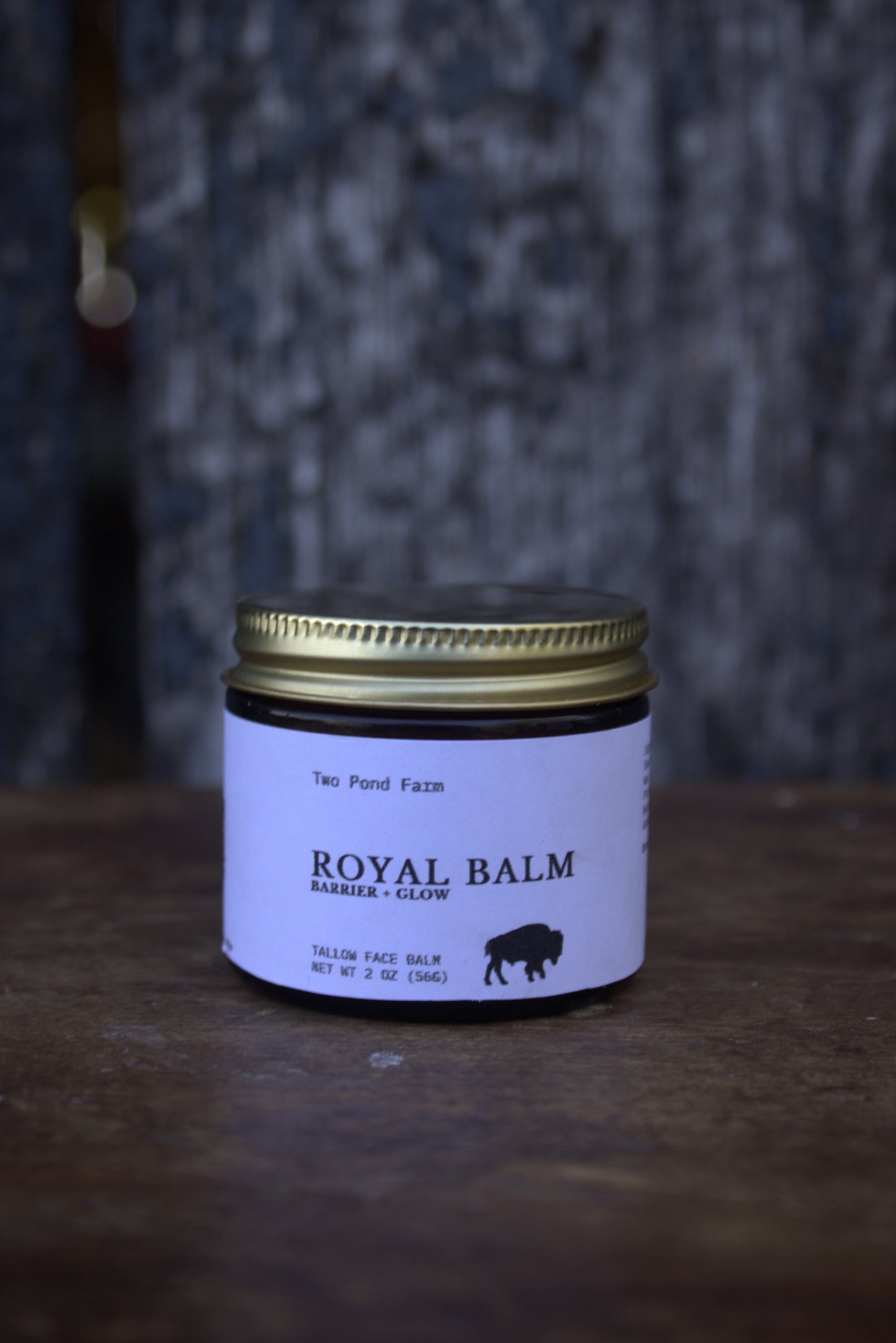 Jar of Royal Balm on a wooden surface with a textured gray background